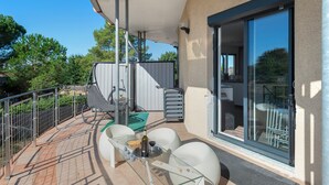 Ein Balkon mit Tisch, Stühlen und einer Glastür, die zu einem Innenraum führt.