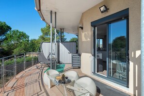 Een balkon met een tafel, stoelen en een glazen deur die naar de binnenruimte leidt.