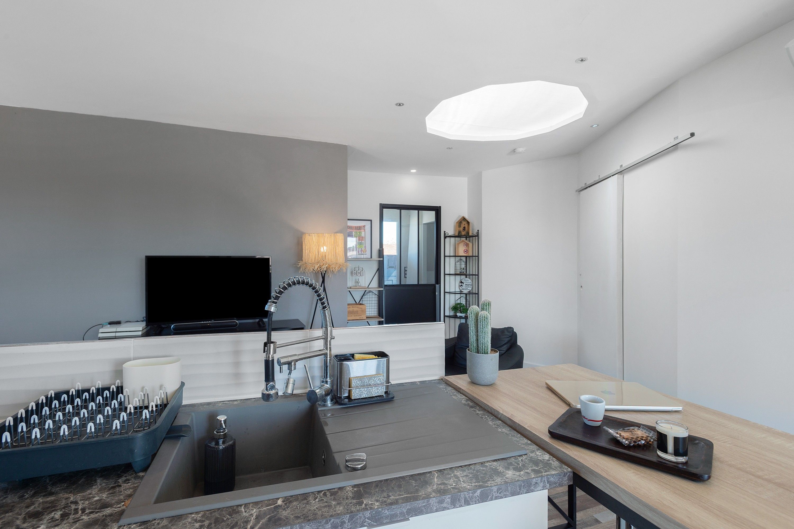 A modern kitchen with a built-in stove, sink, and a flat-screen TV.