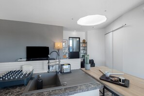 A modern kitchen with a built-in stove, sink, and a flat-screen TV.