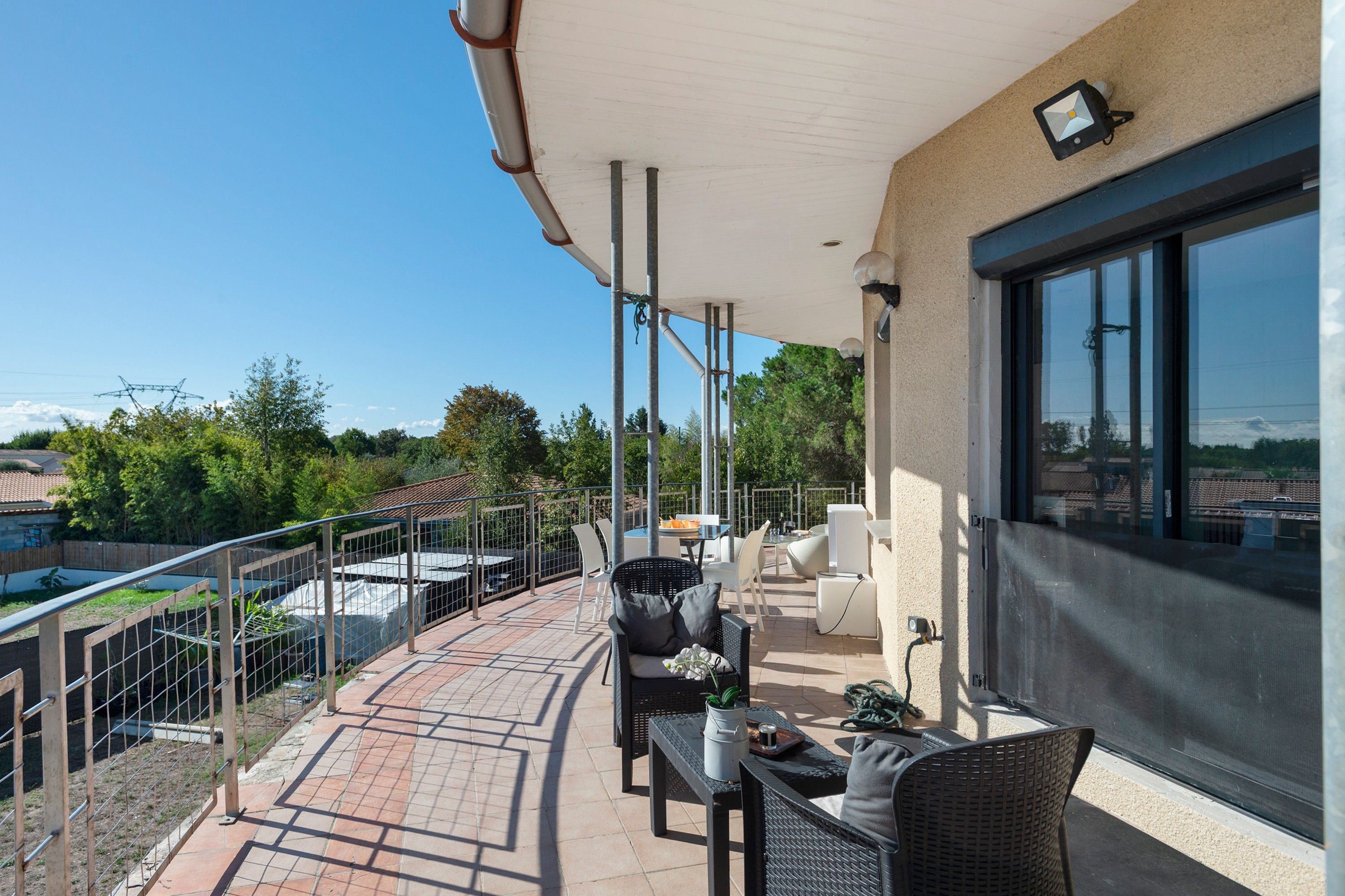 Eine überdachte Terrasse im Freien mit Sitzgelegenheiten, einem Pool und Blick auf die Umgebung.