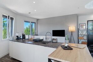 A modern kitchen with a central island, built-in appliances, and a large window providing a view of greenery.