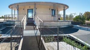 Ein rundes Gebäude mit einer zentralen Treppe, Metallgeländern und einer flachen Dachfläche.