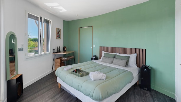 Ein Schlafzimmer mit einem Bett, Nachttischen, einem Schreibtisch und einem Fenster.
