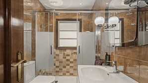 Um banheiro moderno com chuveiro em box de vidro, pia branca e vaso sanitário.