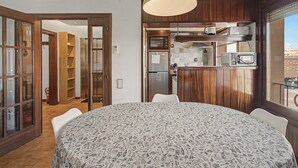 Cozinha compacta com área de refeições, incluindo forno embutido, micro-ondas e luminária pendente.