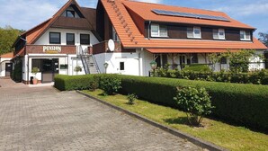 Een gebouw met twee verdiepingen, een schuin dak en een duidelijke ingang, met een bord waarop 'Pension' staat.