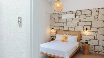 Ein Schlafzimmer mit Steinwand, Holzbettgestell und einer Hängelampe.