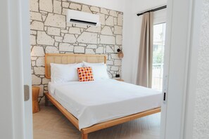 A bed with a stone wall backdrop, a woven headboard, and a window with curtains.