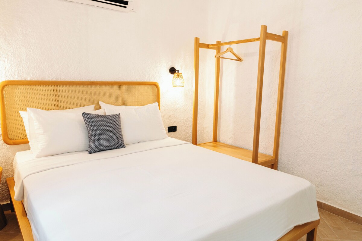 A bed with a wooden headboard, white bedding, and a patterned pillow.