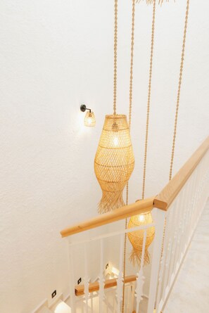 A staircase with a white railing and a hanging light fixture.
