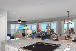A modern kitchen with a built-in stove, a dining area with a view, and a ceiling fan. - Private Pool | Beachfront Decks | Walk to Beach | Cottage By The Sea (St. Joe Beach)