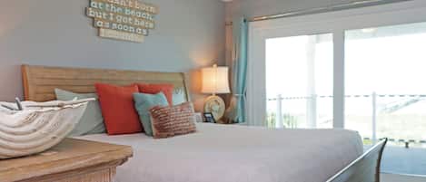 A bedroom with a bed, pillows, a bedside table, a lamp, and a wall with a motivational quote.