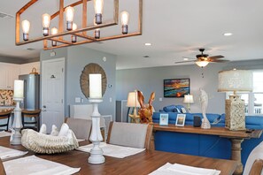 A dining area with a wooden table, white napkins, and a decorative centerpiece. - Private Pool | Beachfront Decks | Walk to Beach | Cottage By The Sea (St. Joe Beach)