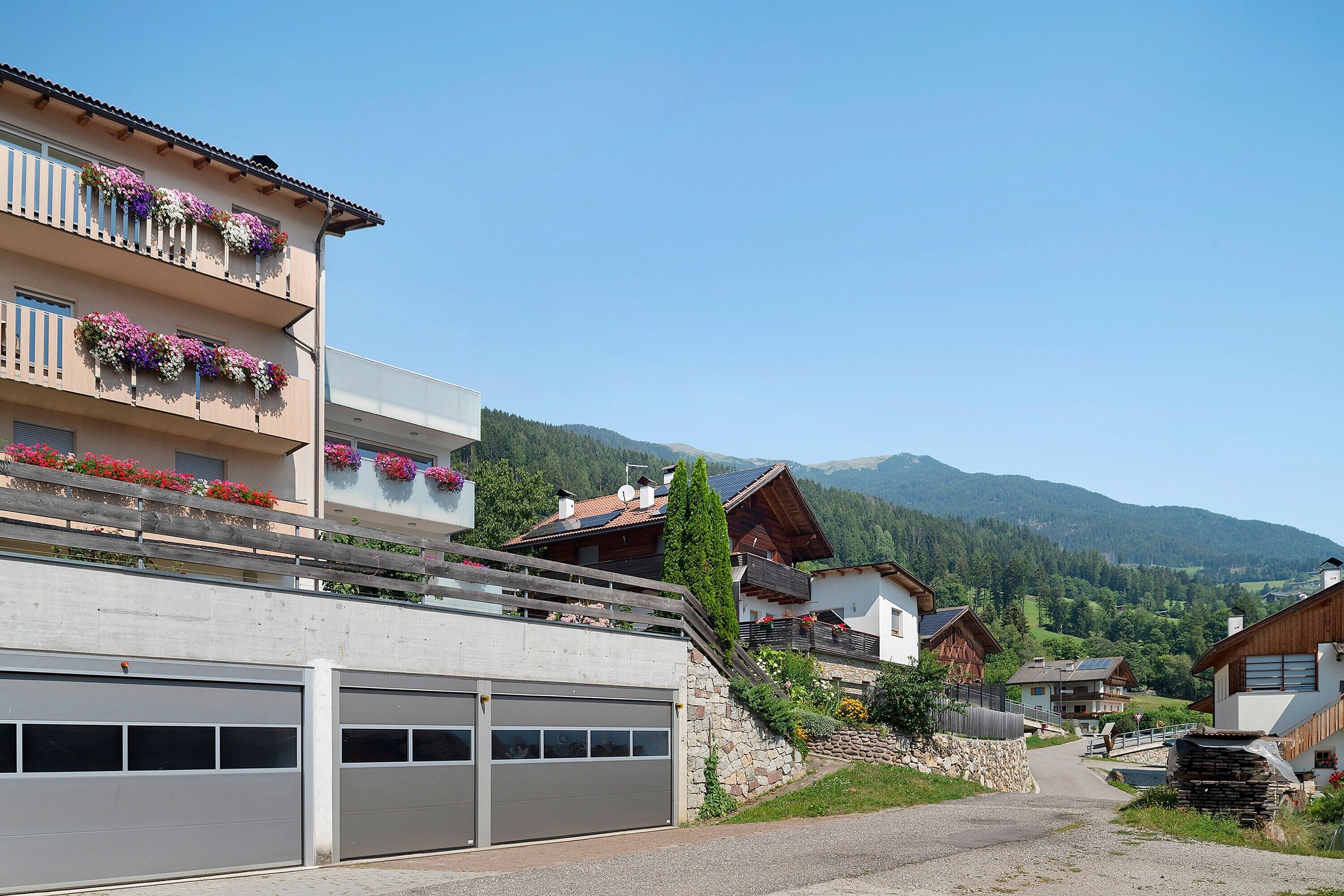 Eine Wohnstraße mit Häusern, einer Garage und einem Berg im Hintergrund.