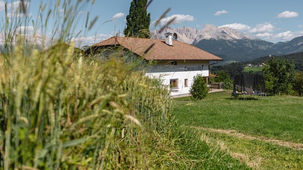 A white building with a red roof, surrounded by grass and mountains in the background. - Holiday Apartment 'Am Oberranhof' with Mountain View, Shared Terrace, and Wi-Fi (Deutschnofen)