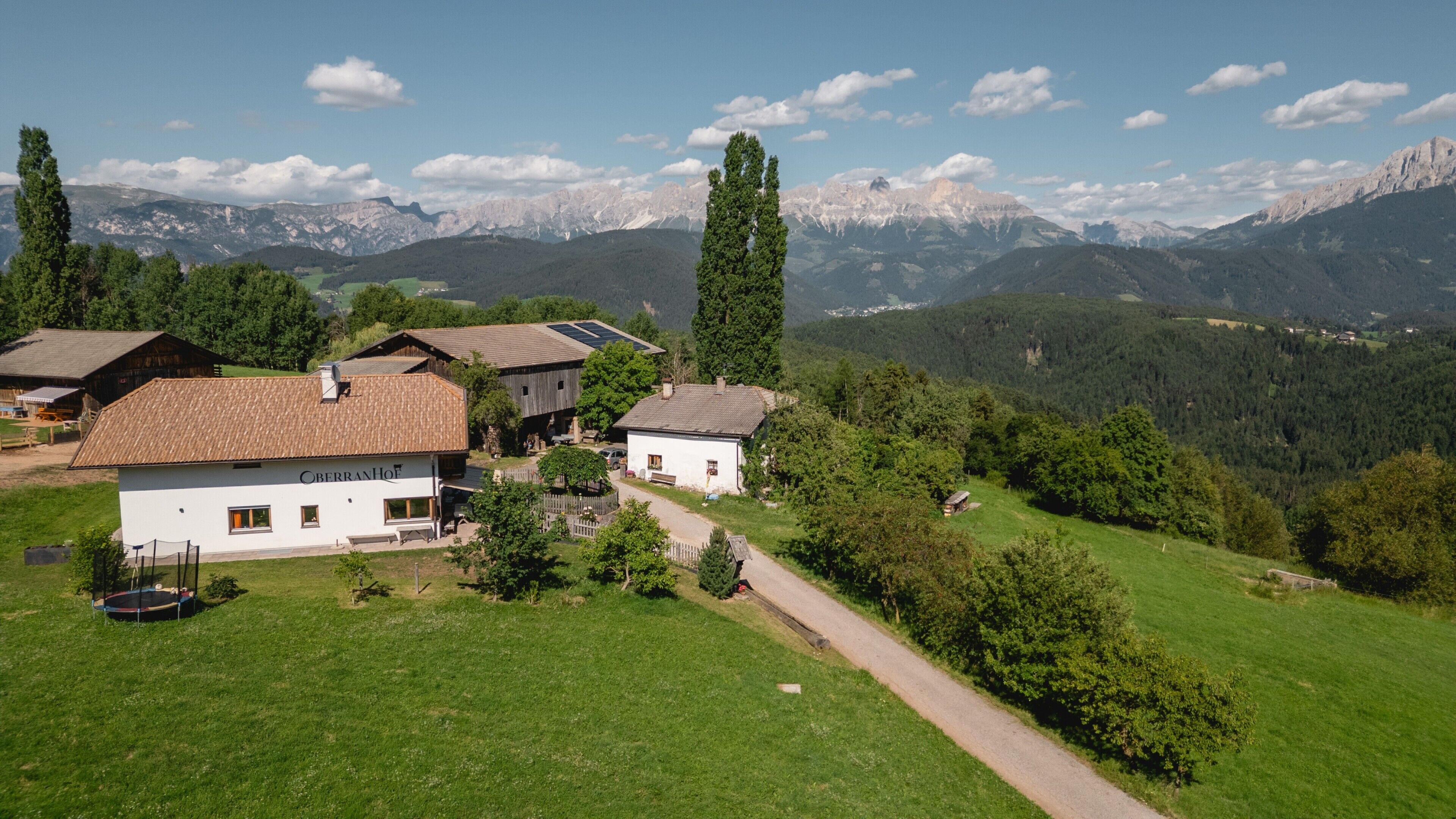 Un pueblo rural de montaña con casas de madera tradicionales, cielo despejado y vistas a montañas nevadas en la distancia.