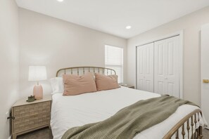 A bedroom with a bed, bedside table, lamp, and a wardrobe.