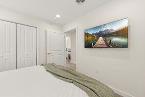 A bedroom with a bed, a painting of a lake and mountains, and white doors. - 6 Bedrooms Perfect for Large Groups (Lafayette)