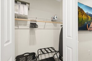 A room with a white door, a black and white chair, a shelf with items, and a painting of a lake. - 6 Bedrooms Perfect for Large Groups (Lafayette)