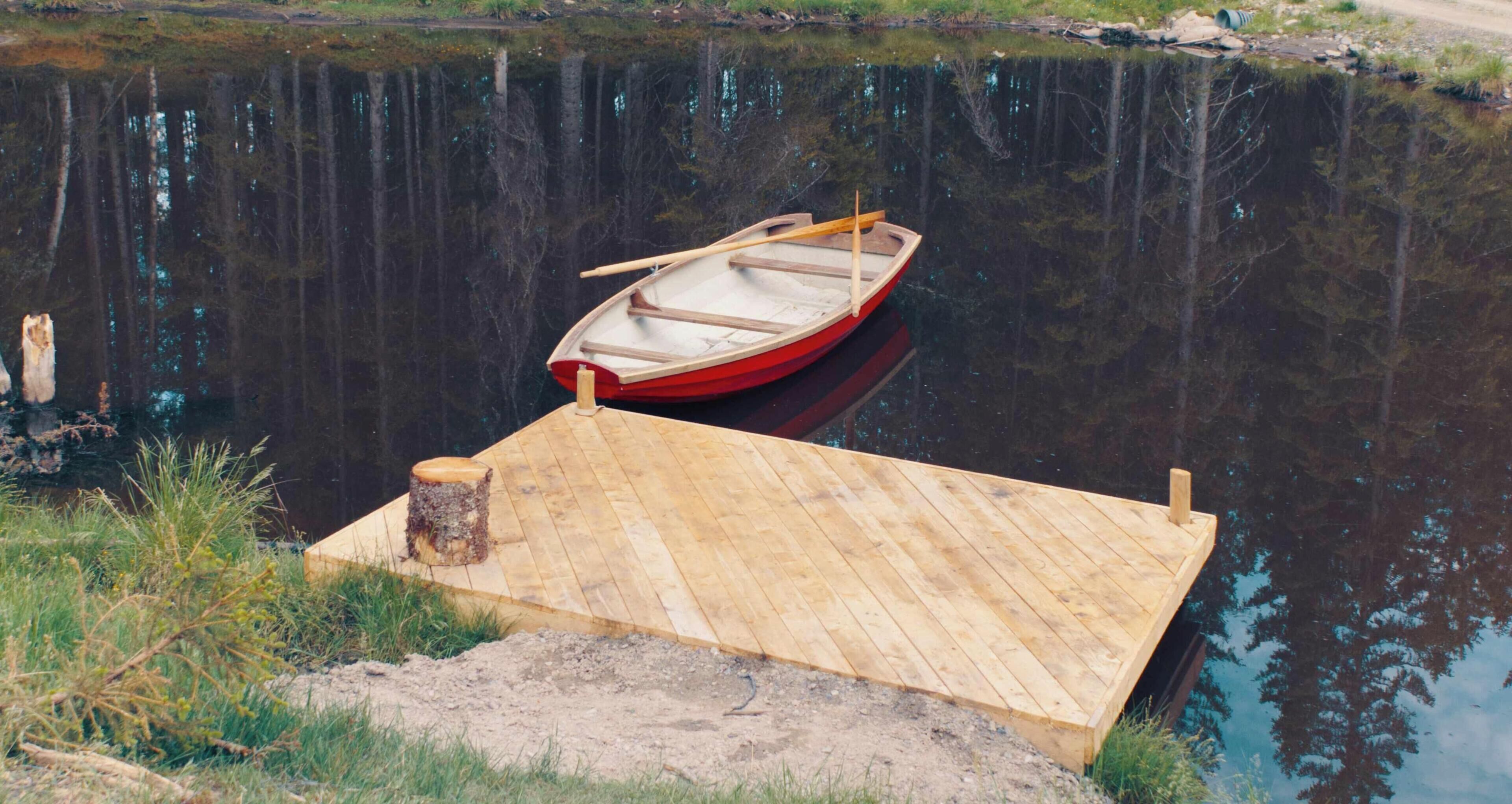 Un muelle de madera que se extiende sobre una masa de agua tranquila, con un pequeño bote amarrado al final.