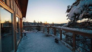 Cubierta nevada con una mesa y sillas, con vista a un paisaje invernal de árboles.