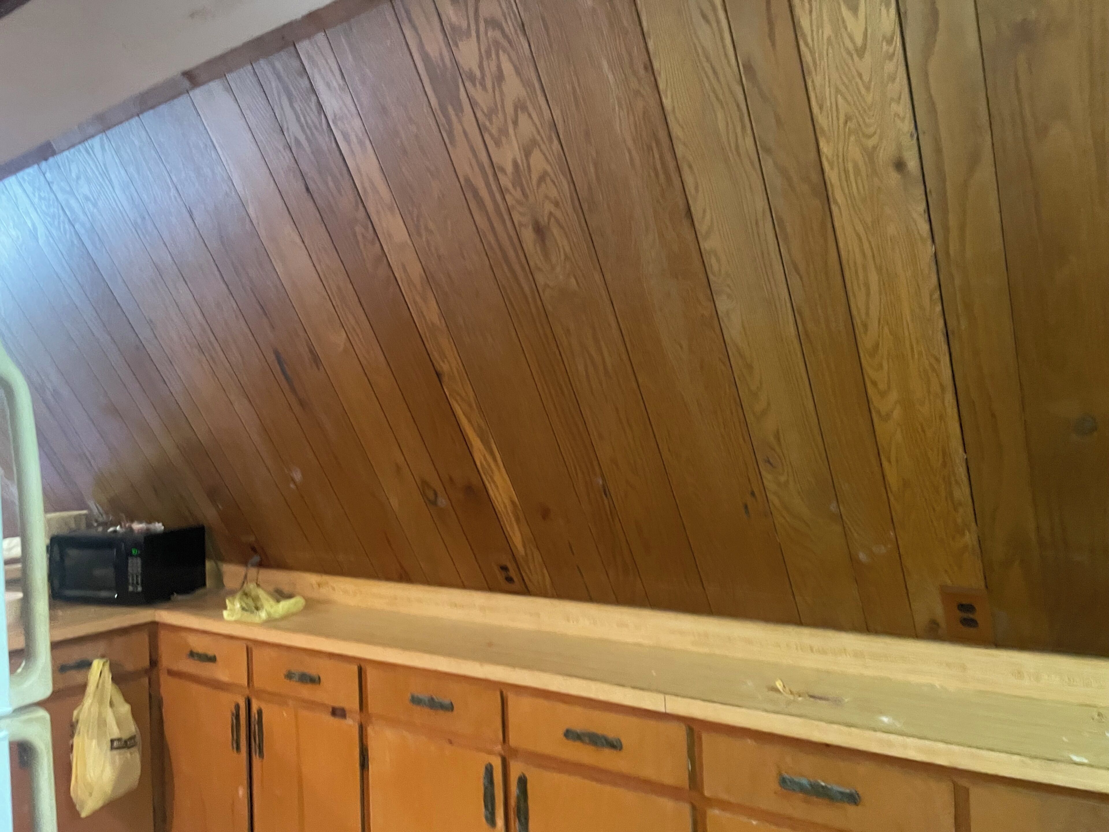 Una habitación con techo de paneles de madera, una encimera de cocina y armarios de madera.