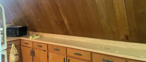 Una habitación con techo de paneles de madera, una encimera de cocina y armarios de madera.