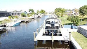 A canal with boats docked on both sides, surrounded by residential houses and greenery. - Waterfront Oasis - Boat, Pool, Hot Tub & Outdoor Living (Cape Coral)