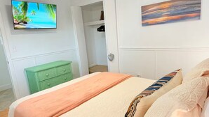 A bedroom with a bed, a television on the wall, and a painting. - Waterfront Oasis - Boat, Pool, Hot Tub & Outdoor Living (Cape Coral)