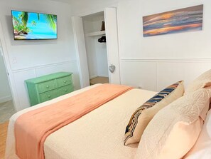 A bedroom with a bed, a television on the wall, and a painting. - Waterfront Oasis - Boat, Pool, Hot Tub & Outdoor Living (Cape Coral)