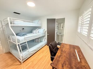 A bunk bed with a desk and chair, a wooden table, and a bathroom with a sink and mirror. - Waterfront Oasis - Boat, Pool, Hot Tub & Outdoor Living (Cape Coral)