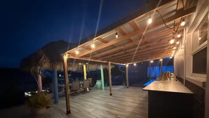 An outdoor patio area with a wooden deck, seating, and a bar area. - Waterfront Oasis - Boat, Pool, Hot Tub & Outdoor Living (Cape Coral)