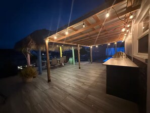 An outdoor patio area with a wooden deck, seating, and a bar area. - Waterfront Oasis - Boat, Pool, Hot Tub & Outdoor Living (Cape Coral)