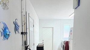 A laundry room with a washing machine, a dryer, and a door with fishing rods and a fish decoration. - Waterfront Oasis - Boat, Pool, Hot Tub & Outdoor Living (Cape Coral)