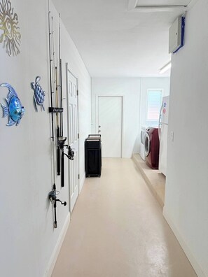 A laundry room with a washing machine, a dryer, and a door with fishing rods and a fish decoration. - Waterfront Oasis - Boat, Pool, Hot Tub & Outdoor Living (Cape Coral)