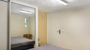 Una habitación con cama, una silla, un armario y una mesita.