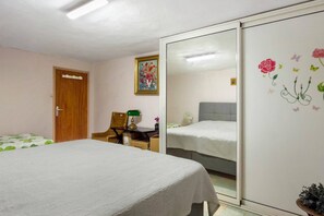 Une chambre à coucher avec un lit, un bureau avec une lampe, une armoire et un tableau au mur.