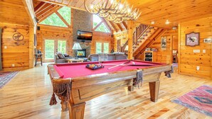 Ein Holzhäuschen mit Poolbillard, Kamin und Treppe.