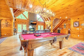 Ein Holzhäuschen mit Poolbillard, Kamin und Treppe.