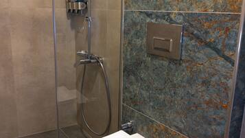 Un baño moderno con ducha de vidrio, inodoro y pared de mármol.