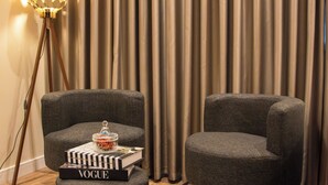 Una sala de estar moderna con dos sillones grises, un pequeño reposapiés y una lámpara de pie.