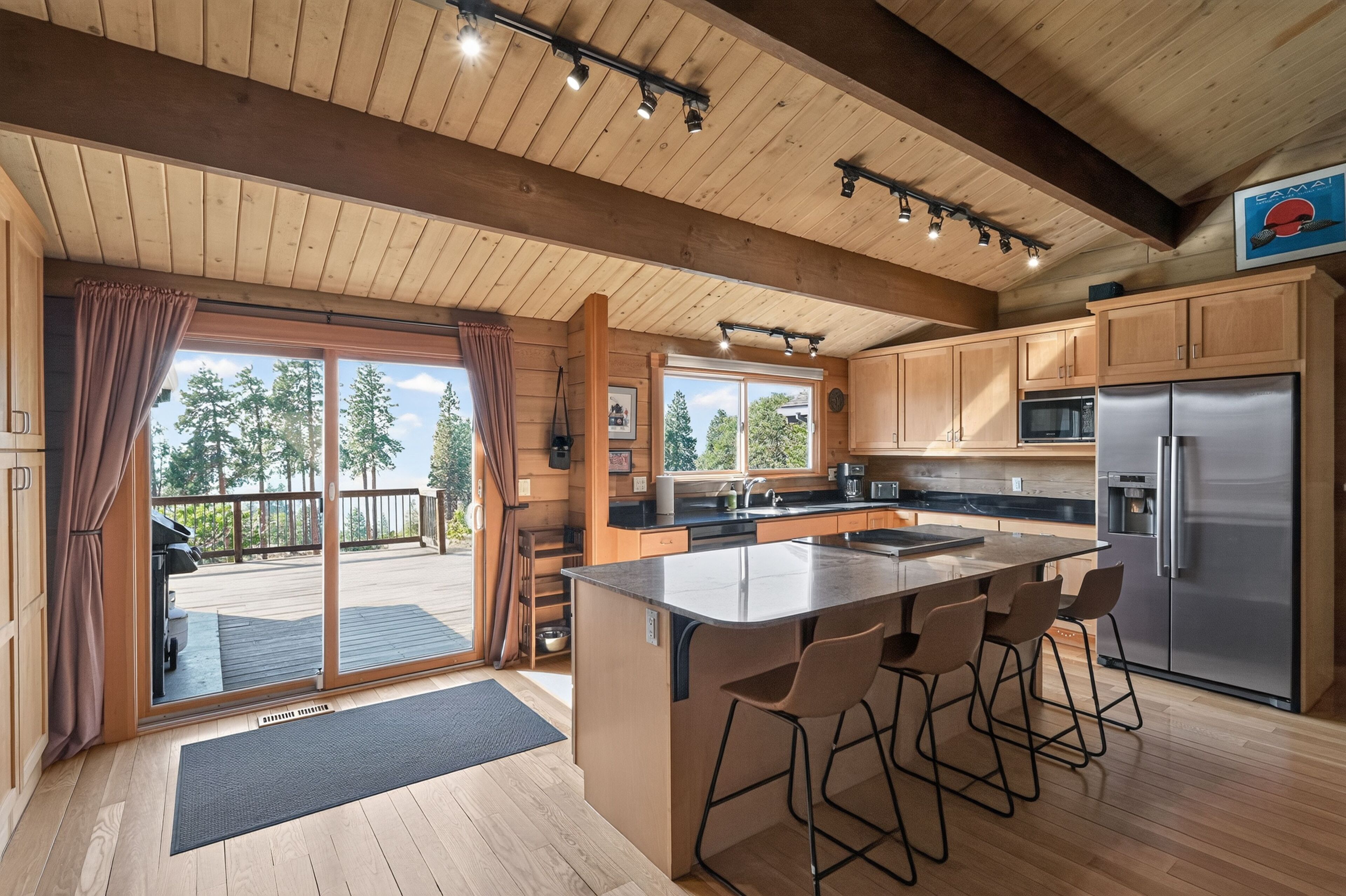 Une cuisine moderne avec des meubles en bois, un réfrigérateur en acier inoxydable et un coin bar avec des tabourets.