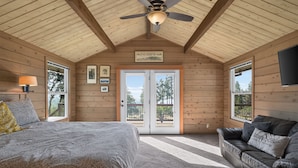 A bedroom with a bed, a ceiling fan, a window, and a door leading outside. - Columbia Gorge - Mosier Bluff | River Views & Pool (Mosier)