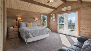 A bedroom with a bed, bedside lamps, a ceiling fan, and a view through a sliding glass door. - Columbia Gorge - Mosier Bluff | River Views & Pool (Mosier)