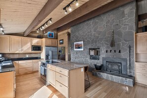 Eine moderne Küche mit Holzschränken, einer Steinwand und einem Kamin.