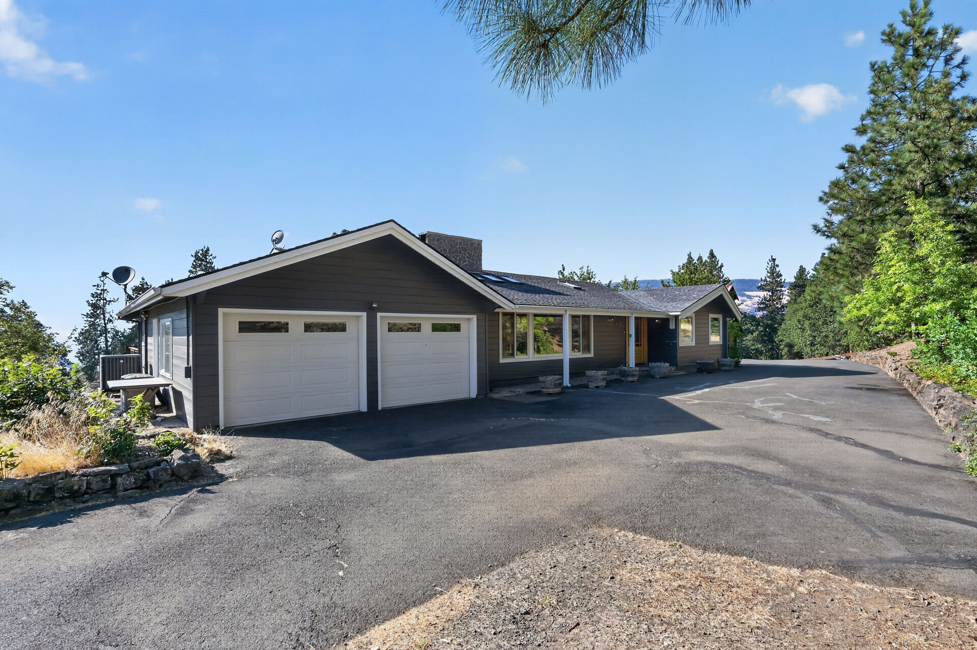 Une maison à deux étages avec un garage, une véranda et une allée menant à un espace de stationnement.