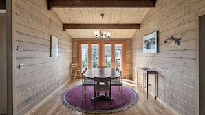 A wooden interior with a round table and chairs, a purple rug, and a fireplace. - Columbia Gorge - Mosier Bluff | River Views & Pool (Mosier)