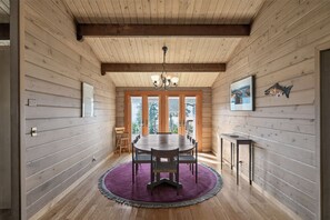 Ein Holzinterieur mit einem runden Tisch, Stühlen, einem violetten Teppich und einem Kamin.