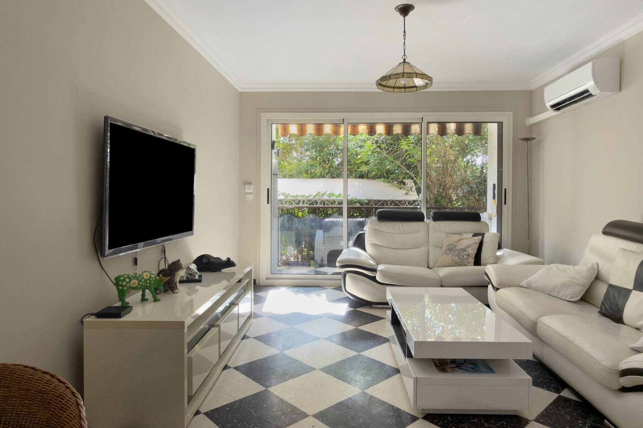 Un salon moderne avec un téléviseur à écran plat, un canapé, une table basse et un sol à motifs.